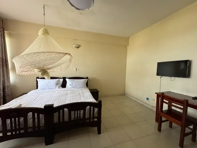Executive Double Room: double bed with a mosquito net, wall-mounted TV and writing desk