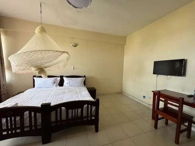 Executive Double Room: bed under a mosquito net, with a desk and chair
