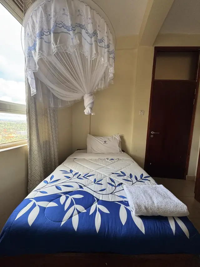 Executive Single Room: made-up single bed with a mosquito net by the window