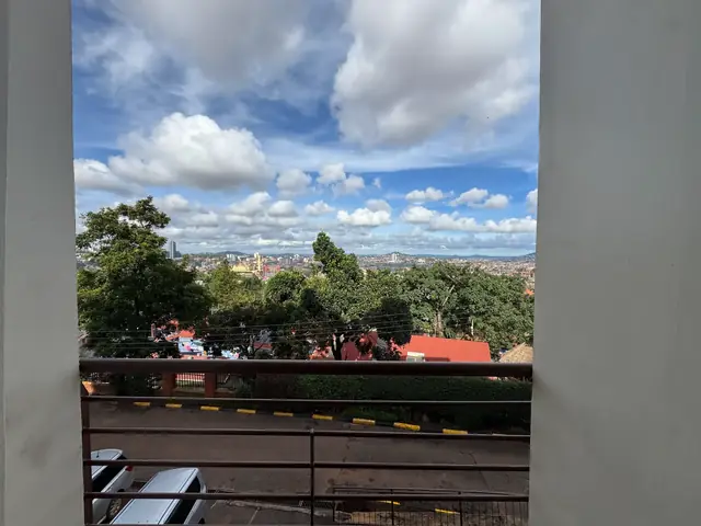 Second-floor balcony view across Kampala under a blue sky
