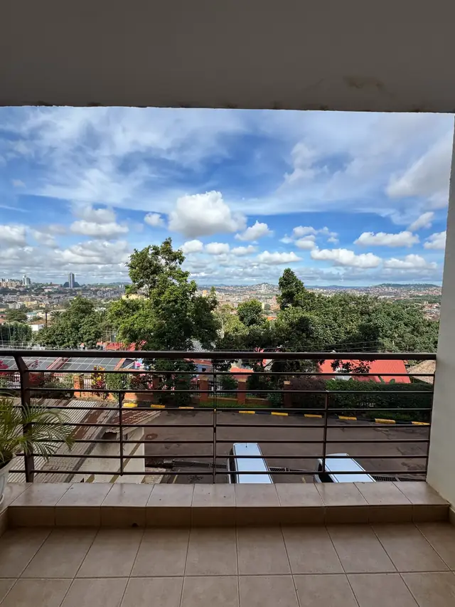 Balcony view from the second floor over treetops to the Kampala skyline